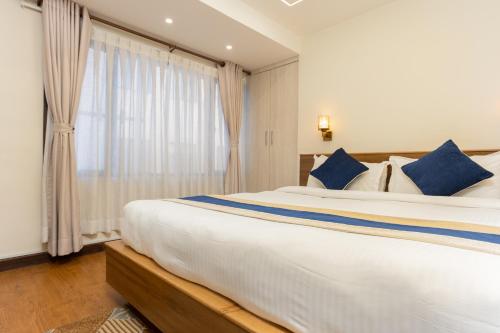 a bedroom with a large white bed with blue pillows at Kathmandu Business Hotel in Kathmandu
