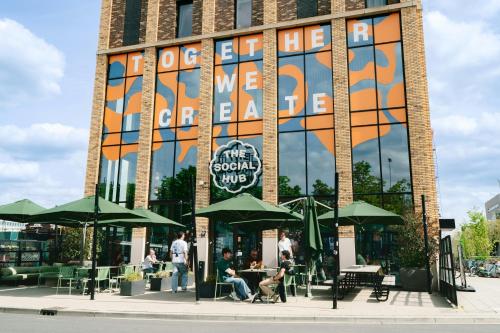a building with people sitting at tables in front of it at The Social Hub Eindhoven in Eindhoven