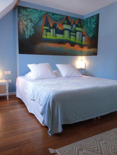 a bedroom with a large bed with a painting on the wall at L'entre-potes in Sully-sur-Loire