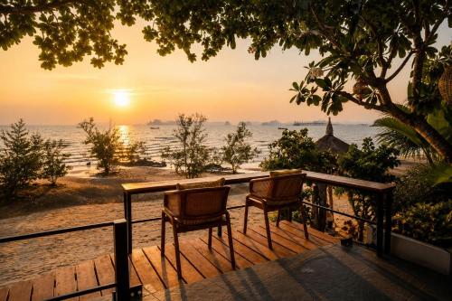 two chairs sitting on a balcony looking at the ocean at Ma's Sea Beach House in Klong Muang Beach