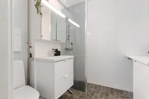 a white bathroom with a toilet and a sink at Central Lapland Apartment By Lapland Host in Rovaniemi