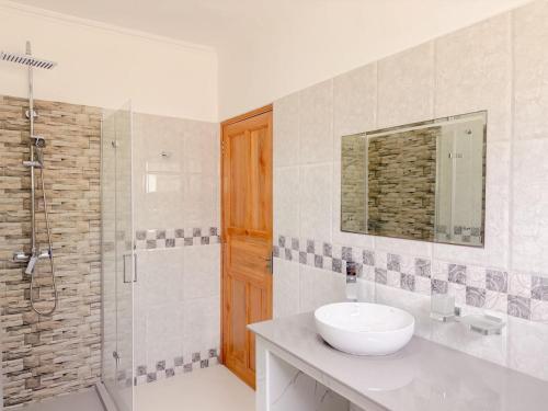 a white bathroom with a sink and a shower at Cove Holiday Apartments in Bel Ombre