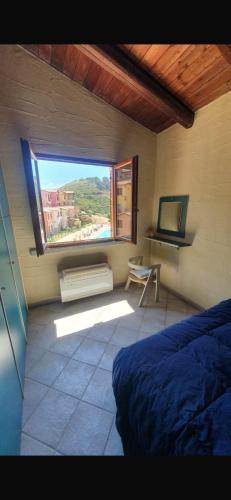 a bedroom with a window and a bed and a desk at La Rosa dei venti in Nebida