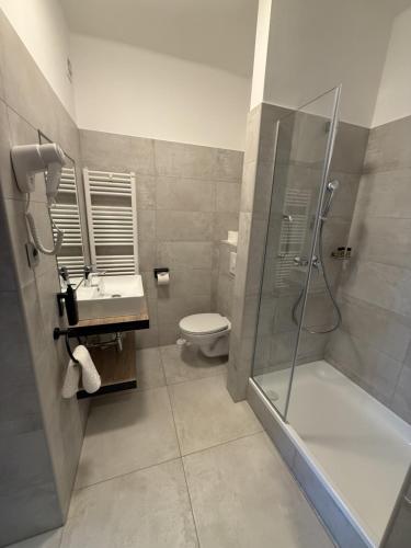a bathroom with a shower and a toilet and a sink at Apartman Hotel in Bük