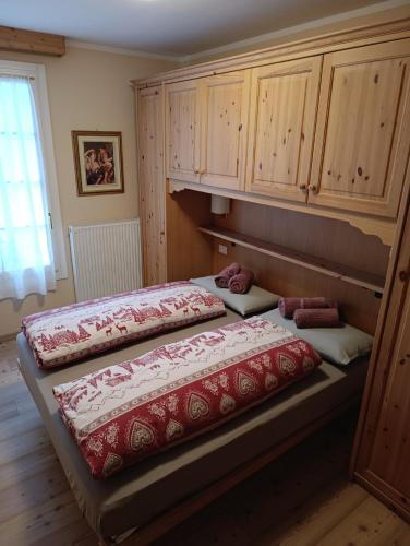 two beds in a room with wooden cabinets at Appartamento Marmolada in Pieve di Livinallongo
