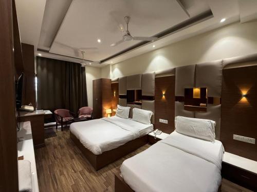 a hotel room with two beds and a desk at Aura Grand Amritsar in Amritsar