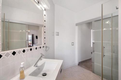 a white bathroom with a sink and a mirror at South Star Guesthouse in Quelfes