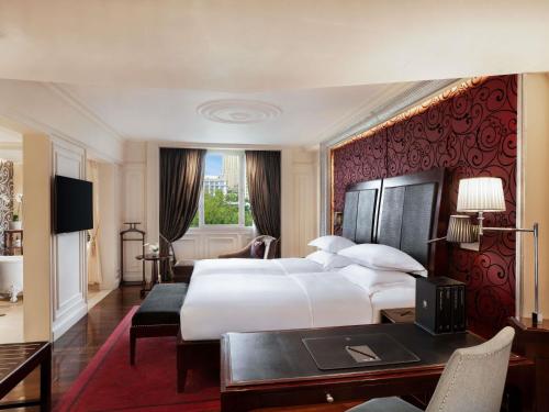 a hotel room with a large bed and a desk at Sofitel Legend Metropole Hanoi in Hanoi
