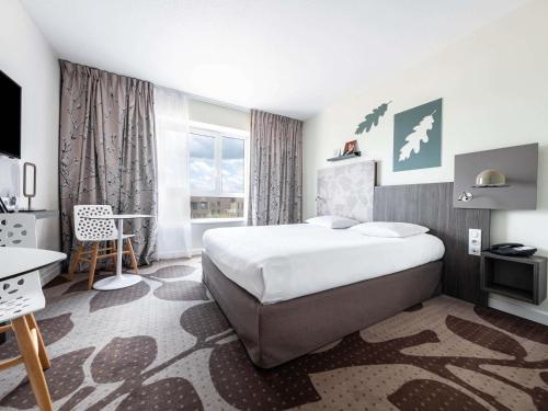 ein Hotelzimmer mit einem großen Bett und einem Fenster in der Unterkunft Mercure Compiègne Sud in Compiègne