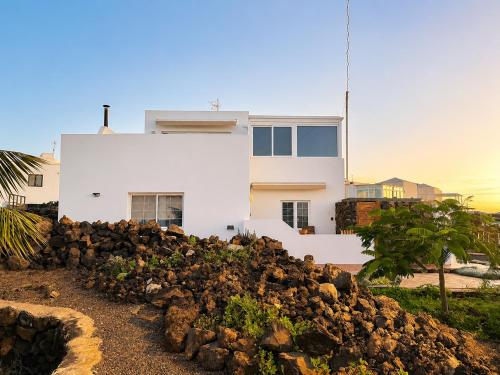 a white house behind a pile of rocks at Casa VEROLES in Tías