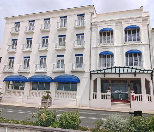 a white building with blue awnings on it at CERISE Royan - Le Grand Hôtel de la Plage in Royan