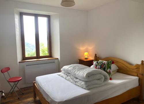 a bedroom with a bed with white sheets and a window at Maison De Fontale in Aleu
