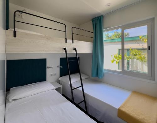 リド・ディ・ダンテにあるCamping Classe Villageの窓付きの寮の部屋に二段ベッドが2つある
