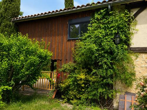 a wooden house with a window and a bush at Les cabanes in Noaillan