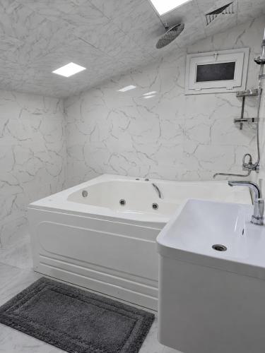 a white bathroom with a tub and a sink at Ganja Comfort Home in Ganja