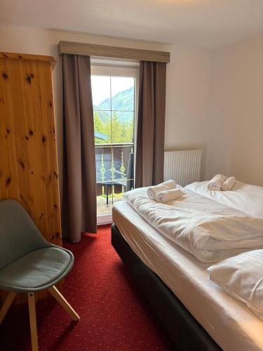 a bedroom with a bed and a chair and a window at Chalet Rotenstein in Berwang