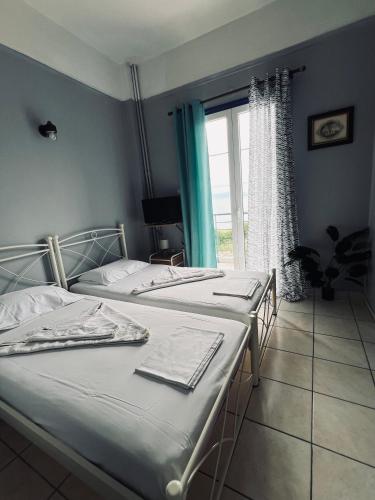 two twin beds in a room with a window at Magklaras Seaside Apartments in Néa Palátia
