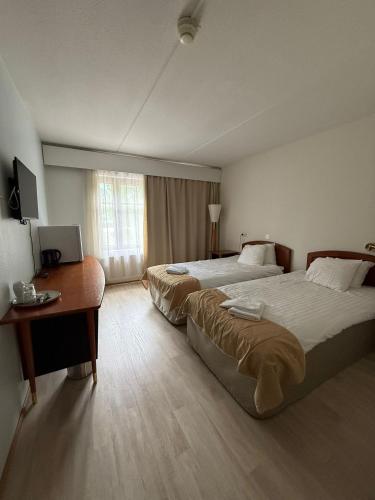 a hotel room with two beds and a desk and a window at Hotelli Patruuna in Imatra