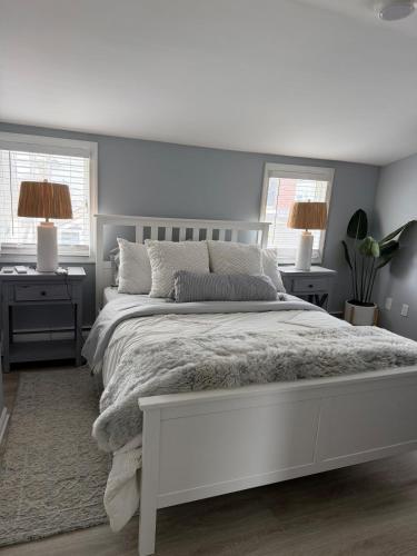 a white bedroom with a white bed and two windows at 2 bedroom beachfront fully refurbished home in East Haven