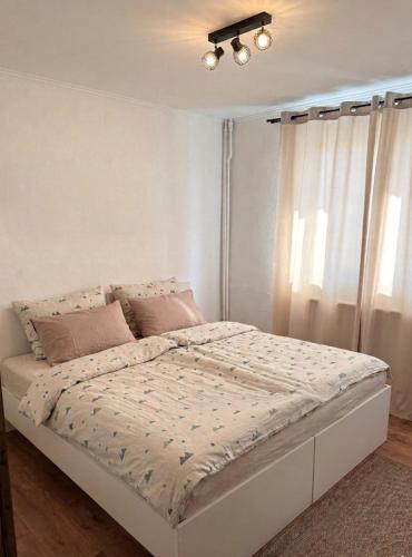 a white bed in a bedroom with a window at Sissi Apartments in Gheorgheni