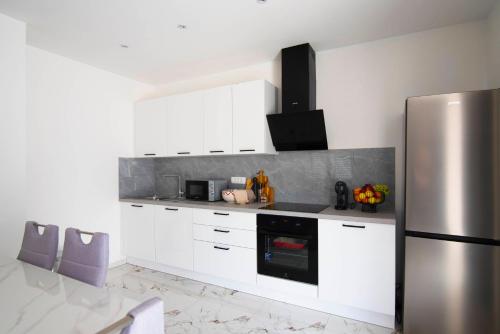 a kitchen with white cabinets and a stainless steel refrigerator at Vacation apartments Mario with salt water pool in Turjaci