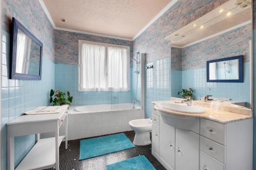a blue bathroom with a tub and a toilet and a sink at Chambres D'hôtes De Kersehen in Plouider