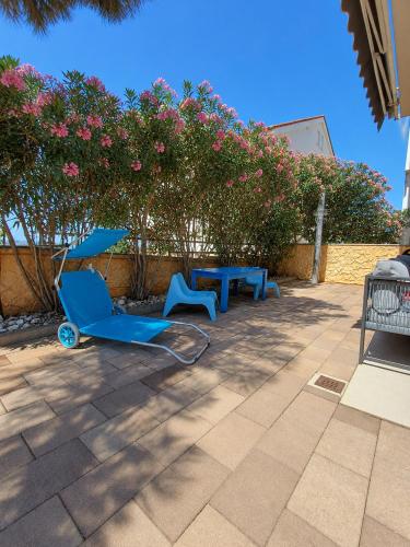 a patio with two blue chairs and a table and flowers at Apartment BruVana in Povljana
