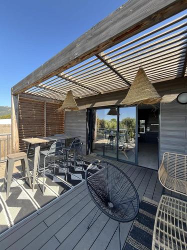 a deck with a table and chairs and an umbrella at Luxurious Duplex With Pool Garden Balcony in Lecci