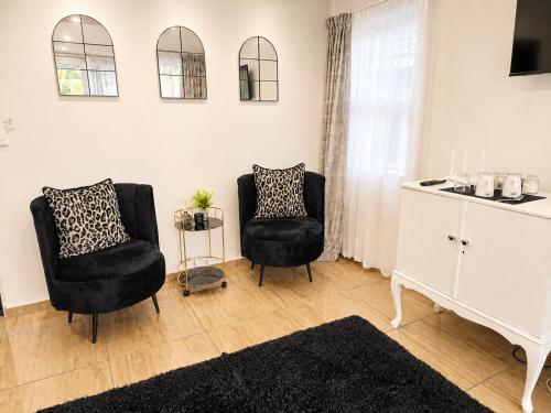 a living room with two chairs and a white cabinet at Zhantique Guest House 2- Unit 10 in Boksburg