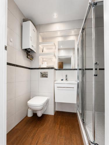 a white bathroom with a toilet and a shower at Apartament Wisła Centrum in Wisła