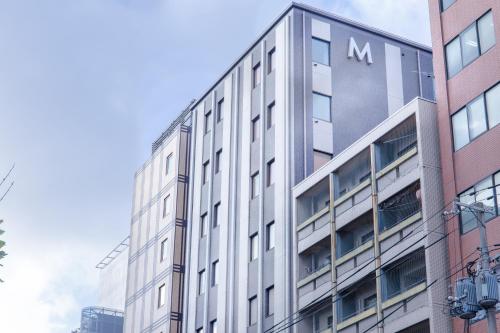 a tall white building with the letter m on it at Hotel M's Plus Shijo Omiya in Kyoto