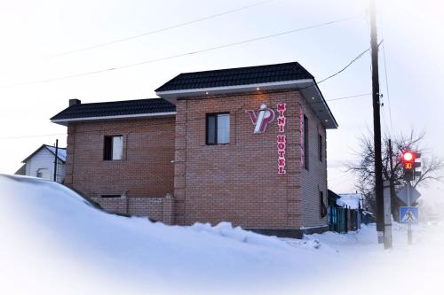 a brick building with a sign on it in the snow at VIP Mini Hotel in Semey