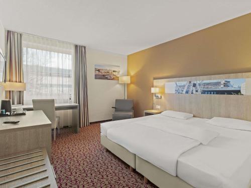 a hotel room with a large bed and a desk at Mercure Hotel Hamburg am Volkspark in Hamburg