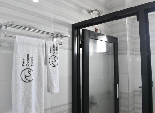 a bathroom with white towels and a glass shower door at Two Oceans Hotel Voi in Voi