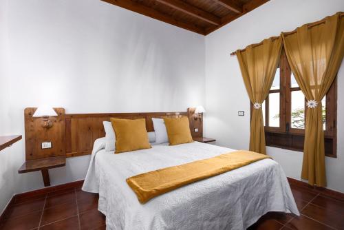 a bedroom with a bed with white sheets and yellow pillows at Home2Book La Molina B, Cozy Country House in Triquivijate