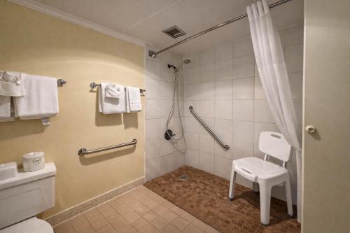 a bathroom with a shower with a toilet and a stool at Motel 6 Rawlins, WY in Rawlins