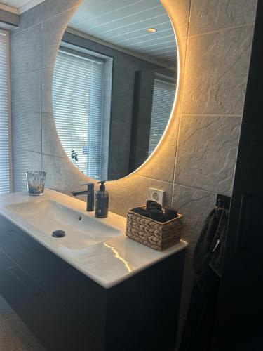 a bathroom with a sink with a round mirror at VillaElvesus in Vossevangen