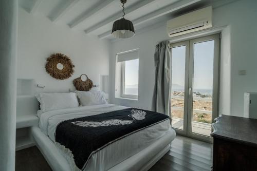 a white bedroom with a bed and a large window at Villa Tonic by Mykonos Mood in Agios Ioannis Mykonos