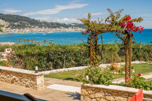 ein Garten mit Pergola und Blick auf das Wasser in der Unterkunft Orientem Villa - Sea View Near Zante Town in Argassi