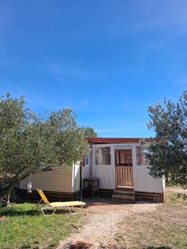 a caravan with a porch and a table and chairs at Mobile Home MEDITERRA in Pirovac