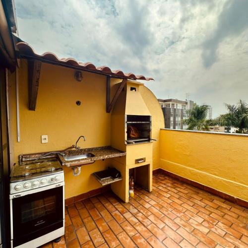 a kitchen with a sink and a stove on a balcony at Cobertura Mangabeiras com vista incrível de BH e área gourmet in Belo Horizonte