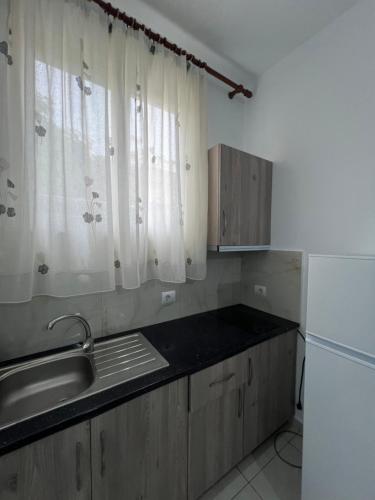 a kitchen with wooden cabinets and a sink and a refrigerator at Grandma's in Sarandë