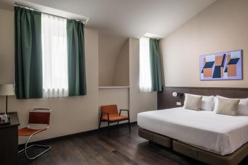 a hotel room with a bed and a chair at BYPILLOW Grand Central in Padova