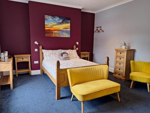 a bedroom with a bed and two chairs at Care Ashore Guest Rooms in Cranleigh