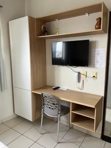 a desk with a television and a chair in a room at Hotel Piracema in Caruaru