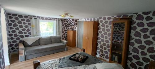 a bedroom with a bed and a couch and a window at Ligzdas in Valgalciems