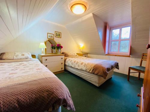 a attic bedroom with two beds and a window at The Kennels Ellary in Lochgilphead