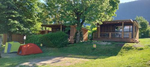 a house with a tent in the grass next to a tree at Camping Onlycamp Au Cœur du Lac - Lac d'Annecy in Sévrier