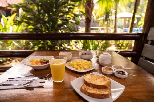 a wooden table with breakfast foods and a glass of orange juice at La Bicok EcoLodge in Mindo