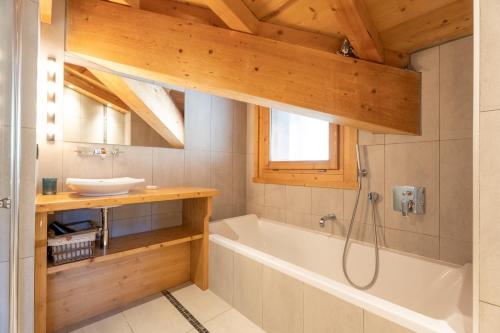 a bathroom with a tub and a sink at Appartement Corniche - MultiPass in Les Gets